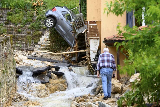 Une carcasse de voiture à la verticale contre une maison de Cressier (NE). [Keystone - Laurent Gillieron]