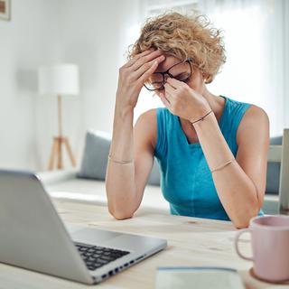 Une femme est effondrée en regardant son ordinateur. [Depositphotos - milangucci]