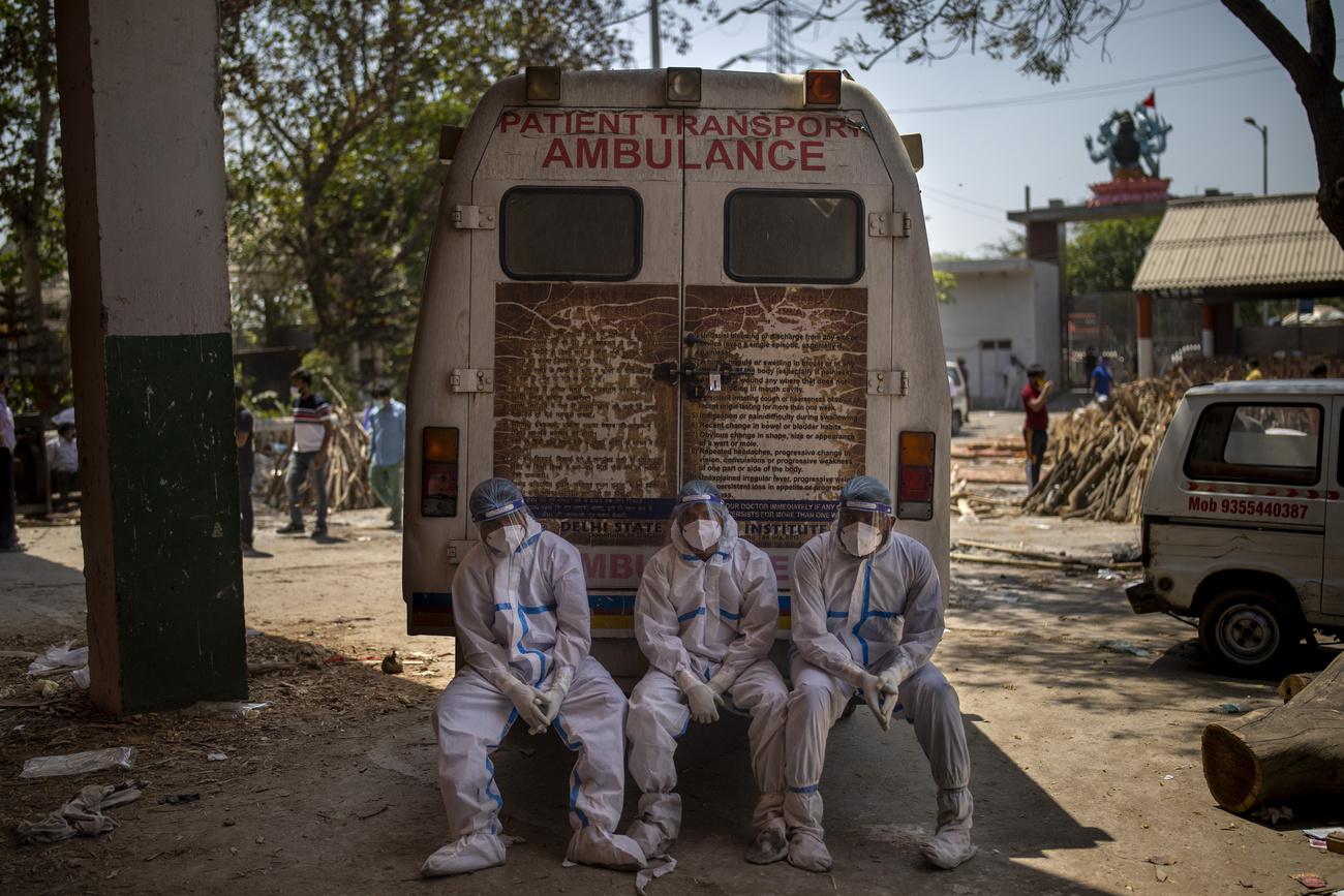 Des travailleurs épuisés se reposent derrière l'ambulance qui vient d'amener des corps destinés à la crémation. New Delhi, le 24 avril 2021. [Keystone/AP photo - Altaf Qadri]