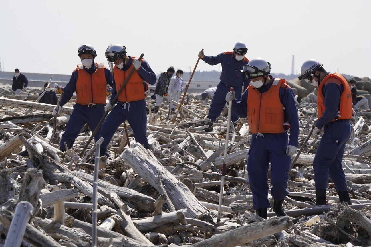 Encore aujourd'hui, la brigade locale des pompiers recherche les corps de personnes disparues le 11 mars 2011. Plage de Namie, Japon, le 11 mars 2021. [Keystone/epa - Kimimasa Mayama]