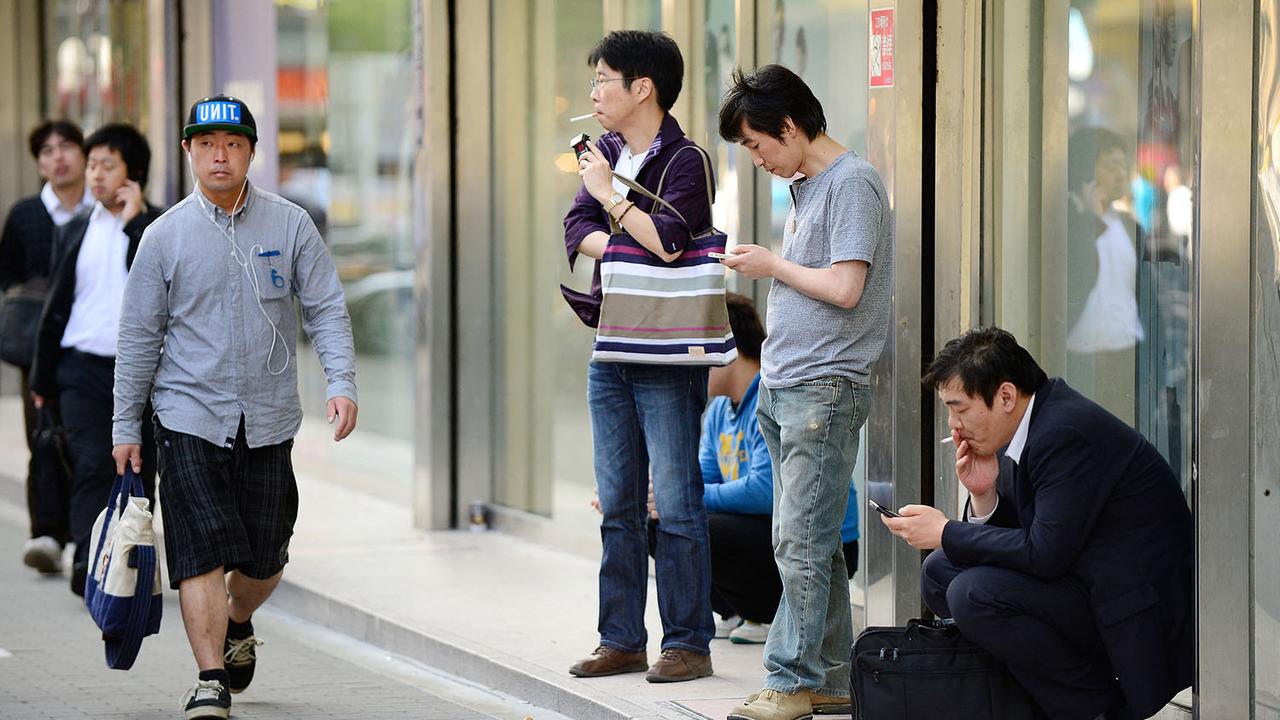 Fumeurs agglutinés sur une petite zone fumeurs dans la rue à Tokyo. [AFP - Toru Yamanaka]