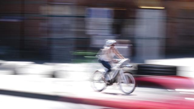 Une femme à vélo. [Keystone - DPA/Frank Molter]