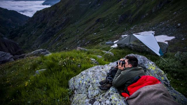 Le président d'OPPAL Jérémie Moulin protège la nuit les moutons de l'éleveur Yves Bruchez contre une attaque du loup, le 28 juillet 2021 sur l'alpage de la Corbassiere dans le Val de Bagnes. [KEYSTONE - JEAN-CHRISTOPHE BOTT]