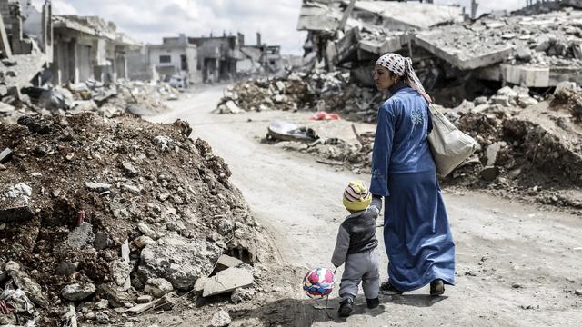 Une femme kurde de Syrie avec son enfant dans les ruines de la ville de Kobane, en mars 2015. [AFP - YASIN AKGUL]