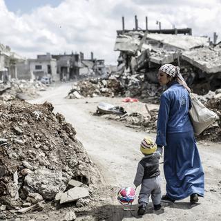 Une femme kurde de Syrie avec son enfant dans les ruines de la ville de Kobane, en mars 2015. [AFP - YASIN AKGUL]