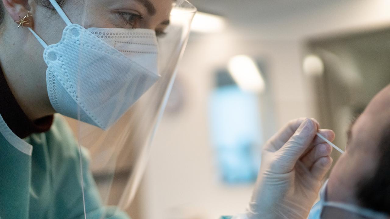 Une pharmacienne en tenue de protection adéquate fait un prélèvement pour un test rapide de l'antigène Covid-19 à Zurich en novembre 2020. [Keystone - Gaetan Bally]