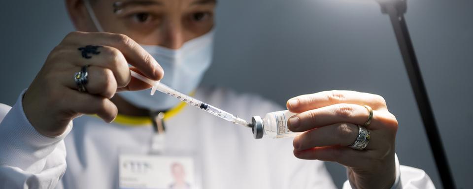 Une infirmière prépare une dose du vaccin Moderna pour un patient lors de l'ouverture des centres de vaccination contre le Coronavirus (Covid-19) en Valais le mardi 2 février 2021 a Sion. [Keystone - Jean-Christophe Bott]