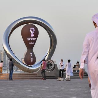Des personnes se rassemblent devant l'horloge du compte à rebours du premier match de la Coupe du Monde de la FIFA 2022 à Doha corniche à Doha, Qatar, le 25 novembre 2021. [EPA/Keystone - Noushad Thekkayil]