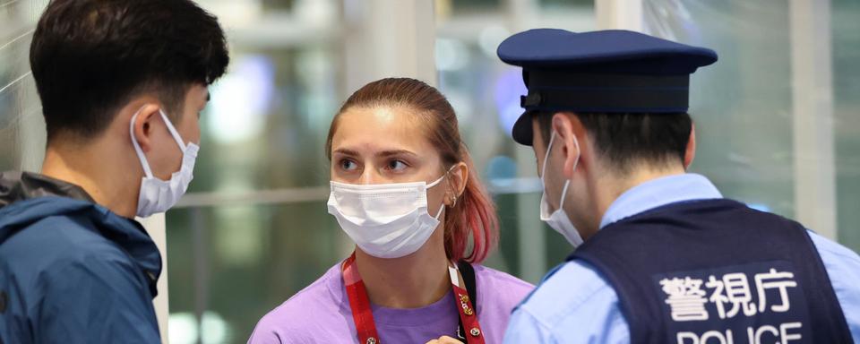 Krystsina Tsimanouskaya parle avec la police japonaise à l'aéroport de Tokyo, le 1 août 2021. [Reuters - Issei Kato]