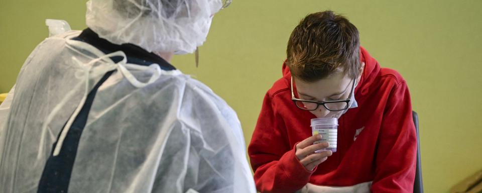 Une infirmière explique à un enfant comment procéder au test salivaire pour la détection du Covid-19, le 1er mars 2021 à Lavoncourt (est de la France). [AFP - Sébastien Bozon]