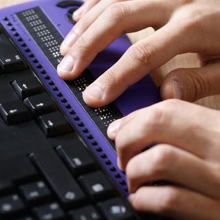 Gros plan sur des mains tapant sur un clavier pour personnes malvoyantes. [Depositphotos - zlikovec]