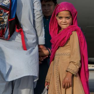 Une enfant attend avec sa famille pour embarquer dans un avion américain, sur la base aérienne de Al Udeid. Qatar, le 22 août 2021. [Keystone/AP - Airman 1st Class Kylie Barrow/U.S. Air Force]
