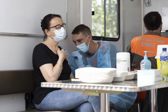 Un agent de la protection civile vaccine une personne sur le parking d'un magasin lors d'une campagne de vaccination de proximité, le mercredi 7 juillet 2021 à Yverdon-les-Bains. [Keystone - Cyril Zingaro]