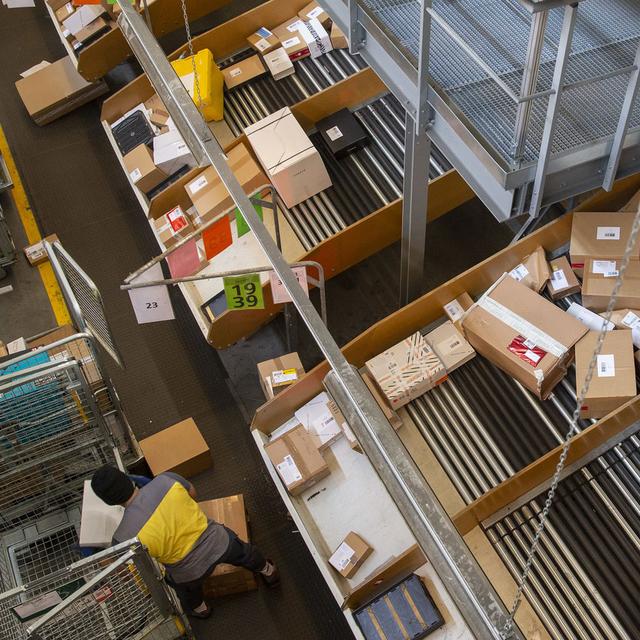 Un employe de La Poste trie les colis au centre colis Daillens de la Poste. [Keystone - Salvatore Di Nolfi]