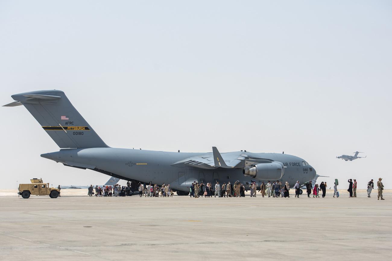 Des personnes réfugiées en provenance d'Afghanistan débarquent sur la base militaire d'Al Udeid. Qatar, le 23 août 2021. [Keystone - Airman 1st Class Kylie Barrow/US Air Force via AP]