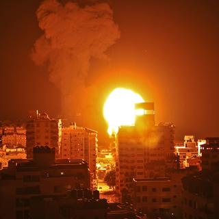 Fumée et boule de feu s'élèvent des points d'impact de roquettes lancées par Israël sur la ville de Gaza, pendant la nuit du 16 au 17 mai 2021. [AFP - Mahmud Hams]