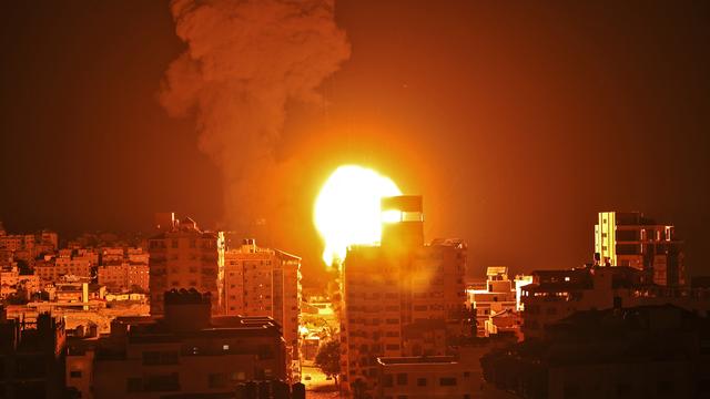 Fumée et boule de feu s'élèvent des points d'impact de roquettes lancées par Israël sur la ville de Gaza, pendant la nuit du 16 au 17 mai 2021. [AFP - Mahmud Hams]