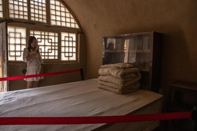 Une femme photographie un lit dans l'ancienne maison de Mao Zedong à Yan'an, le 13 juin 2021. [EPA/Keystone - Roman Pilipey]