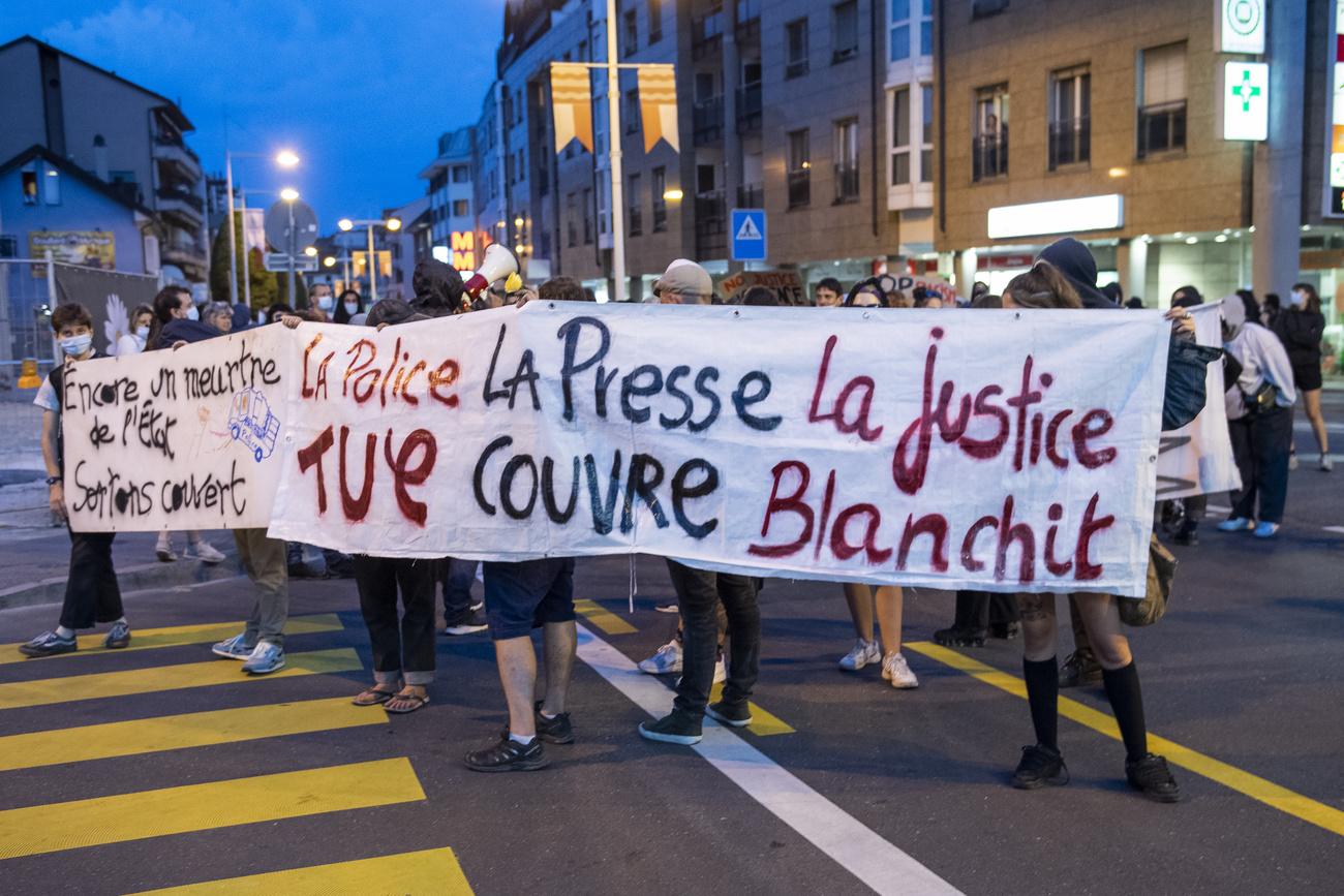 Des manifestants brandissent une banderole "La police tue, la presse couvre, la justice blanchit" lors d'un rassemblement contre la police à Morges. [KEYSTONE - JEAN-GUY PYTHON]