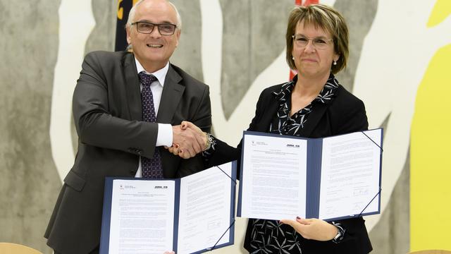 Le Conseiller d'Etat bernois Pierre Alain Schnegg et la présidente du Gouvernement jurassien Nathalie Barthoulot prennent la pose avec les Feuilles de route signées. [Keystone - Anthony Anex]