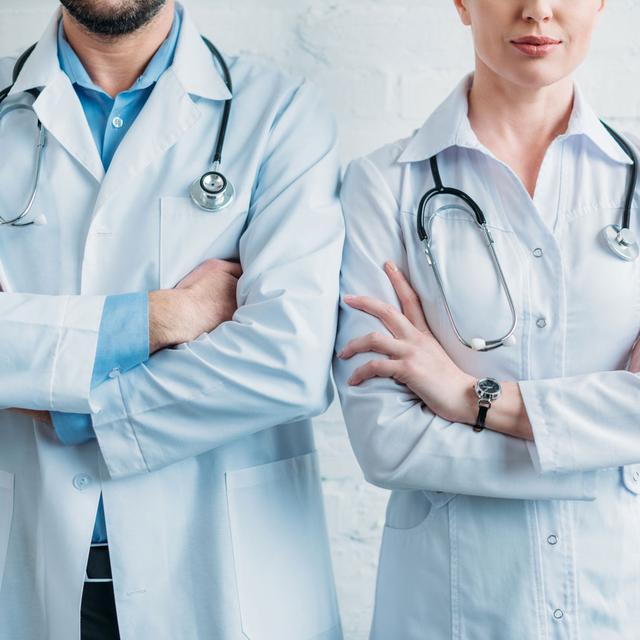 Deux médecins homme et femme posent les bras croisés. [Depositphotos - VitalikRadko]