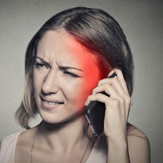 Une femme semble avoir mal à la tête à cause des ondes émises par son téléphone. [Depositphotos - SIphotography]