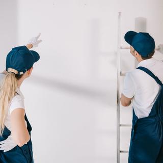 Une femme et un homme s'apprêtent à peindre un mur. [Depositphotos - IgorVetushko]