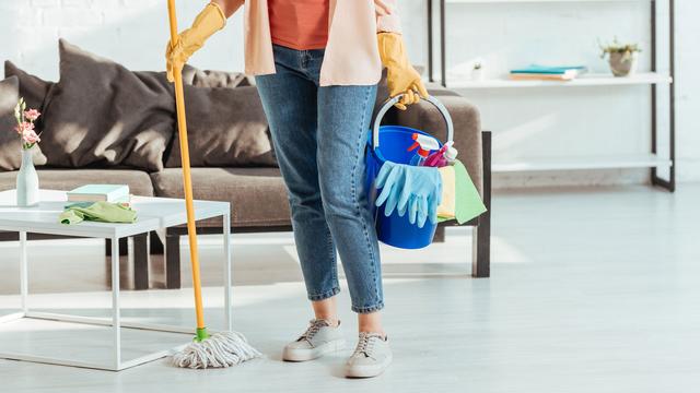 Une employée de maison pose dans un salon, la panosse à la main. [Depositphotos - AllaSerebrina]