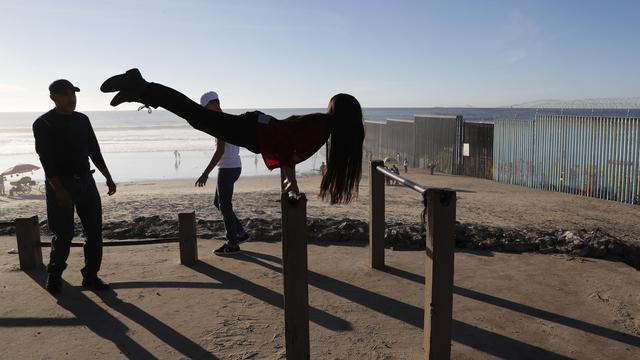 Une femme mexicaine s'entraîne aux barres parallèles devant le mur marquant la frontière entre les Etats-Unis et le Mexique, à Tijuana. (image d'illustration) [AP Photo/Keystone - Rebecca Blackwell]