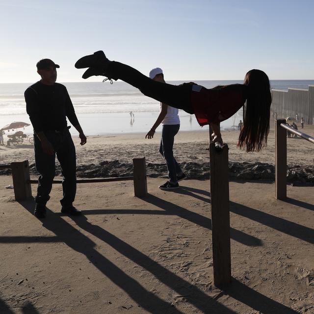 Une femme mexicaine s'entraîne aux barres parallèles devant le mur marquant la frontière entre les Etats-Unis et le Mexique, à Tijuana. (image d'illustration) [AP Photo/Keystone - Rebecca Blackwell]