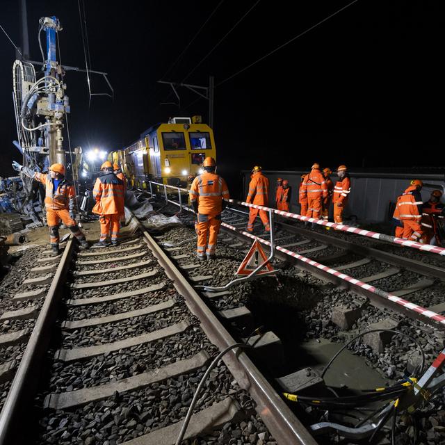 Des ouvriers préparent le ballast pour boucher le trou sur la ligne CFF entre Lausanne et Genève. [Keystone - Jean-Christophe Bott]