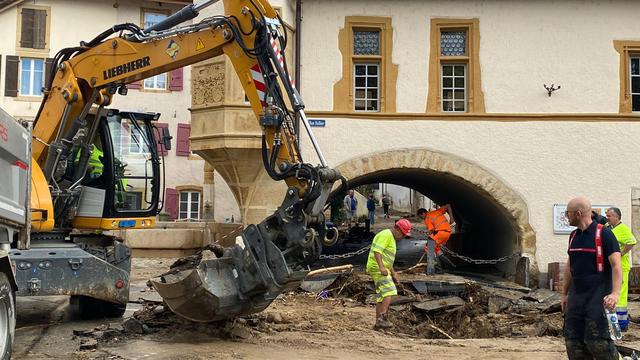 Une pelleteuse déblaie la rue principale de Cressier (NE). [RTS - Stéphane Deleury]