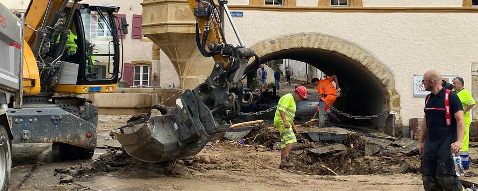 Une pelleteuse déblaie la rue principale de Cressier (NE). [RTS - Stéphane Deleury]