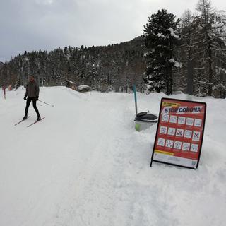 Un panneau demandant le respect des distances sur une piste de ski de fond de Pontresina, dans les Grisons. [Keystone - Salvatore Di Nolf]