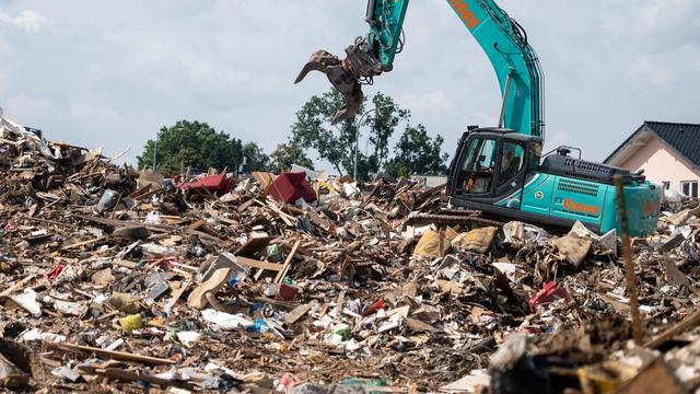 Mardi 27 juillet: une pelleteuse roule sur un énorme tas de débris à Swisttal, Rhénanie-du-Nord-Westphalie (D), fortement touchée par les inondations de la semaine dernière. [Keystone/DPA - Marius Becker]