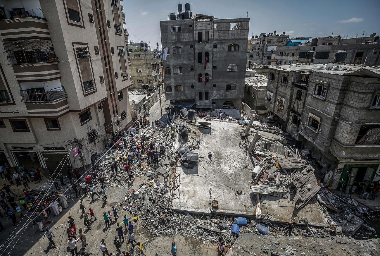 Des Palestiens inspectant une maison détruite par des frappes aériennes israéliennes dans le nord de Gaza, le 20 mai 2021. [EPA/Keystone - Haitham Imad]