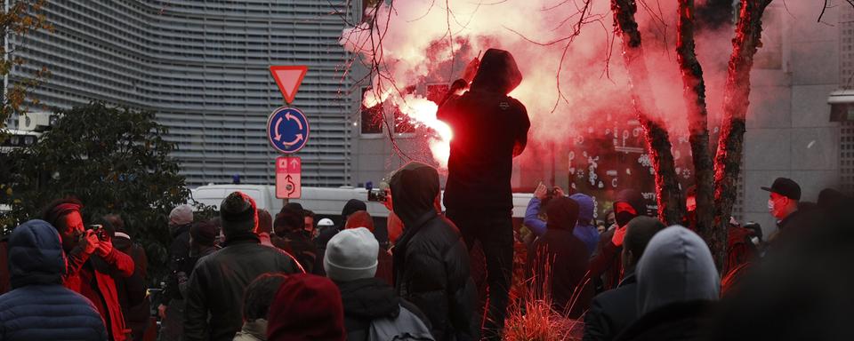 Un protestataire alllume une torche durant la manifestation à Bruxelles, dimanche 21.11.2021. [AP/Keystone - Olivier Matthys]