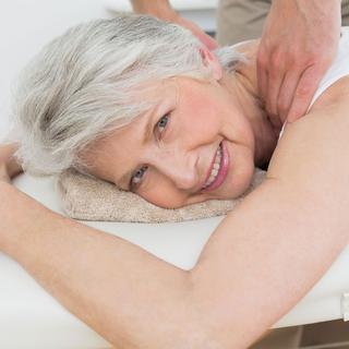 Femme âgée d'une soixantaine d'années en train de se faire masser. [Depositphotos - lightwavemedia]