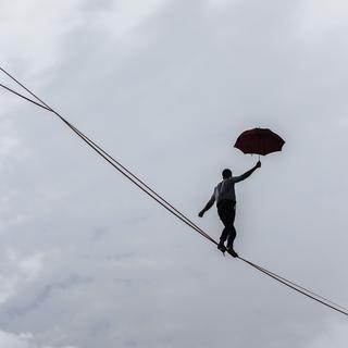 L'acrobate français Nathan Paulin marche sur un cable en tenant un parapluie. [AP Photo/Keystone - Lewis Joly]