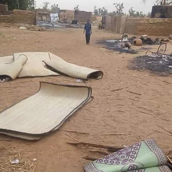 Un garçon traverse le village de Tchombangou, au Niger, ravagé après une attaque terroriste qui a fait une centaine de morts. [EPA/Keystone]