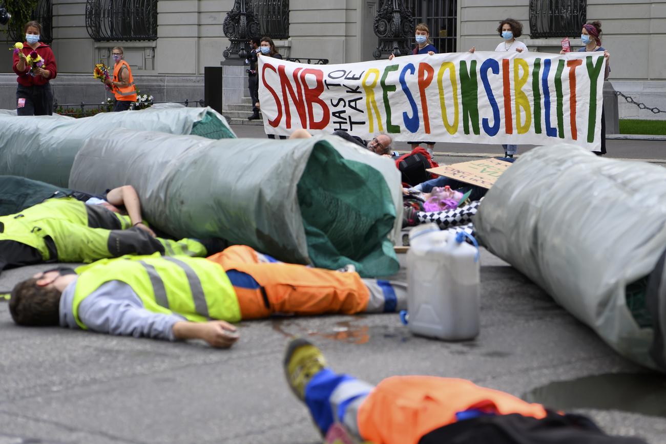 Des activistes manifestent face à la BNS à côté d'une réplique d'un pipeline, le 6 août à Berne. [Keystone - Anthony Anex]