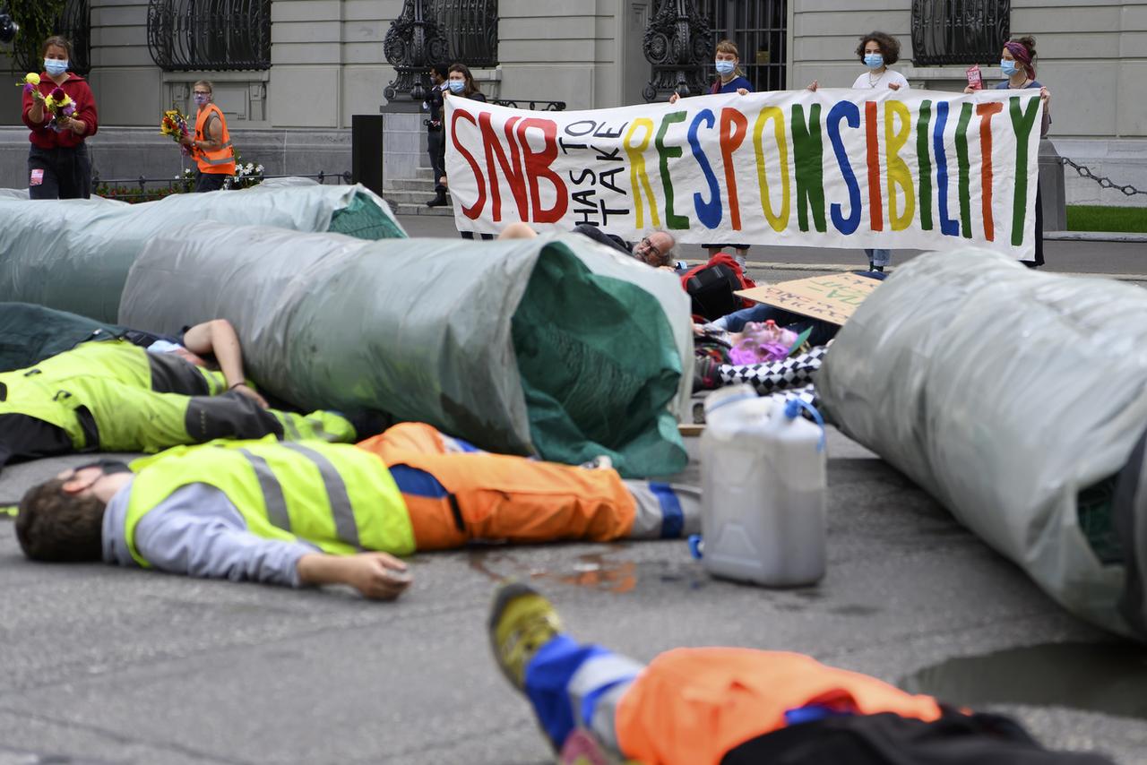 Des activistes manifestent face à la BNS à côté d'une réplique d'un pipeline, le 6 août à Berne. [Keystone - Anthony Anex]