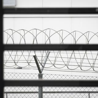Une clôture en fil de fer barbelé devant une fenêtre d'une salle de séjour de l'unité pour mineurs de la prison régionale de Thoune, le mercredi 7 juillet 2021. [Keystone - Peter Klaunzer]