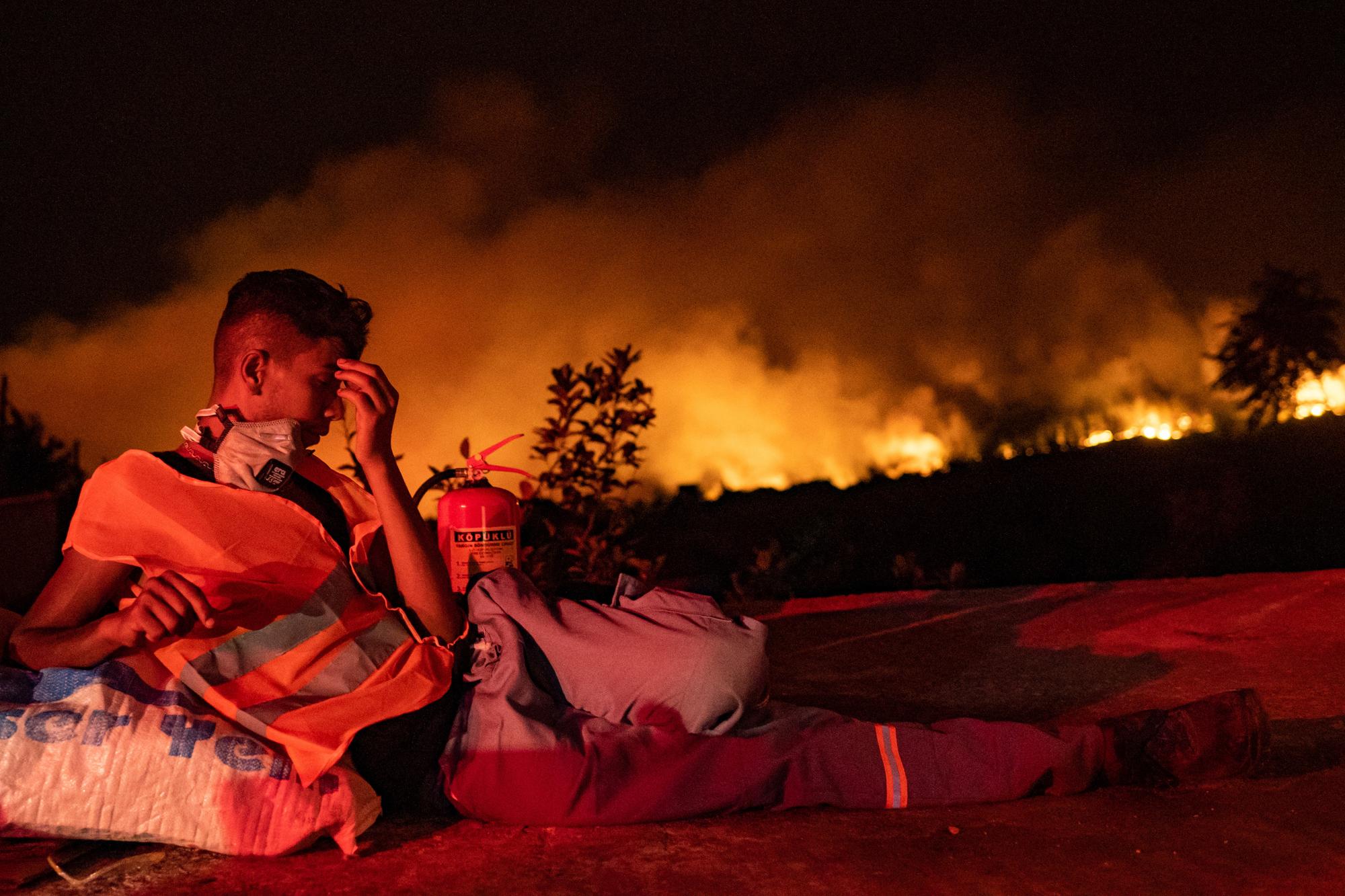 Un secouriste prend une pause alors que les flammes font rage dans la province de Mugla, en Turquie. [AFP - Yasin Akgul]