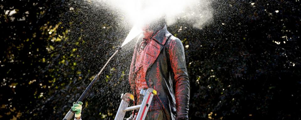 La statue de David de Pury éclaboussée de peinture rouge en plein nettoyage. [Keystone - Laurent Gillieron]