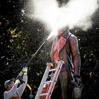 La statue de David de Pury éclaboussée de peinture rouge en plein nettoyage. [Keystone - Laurent Gillieron]