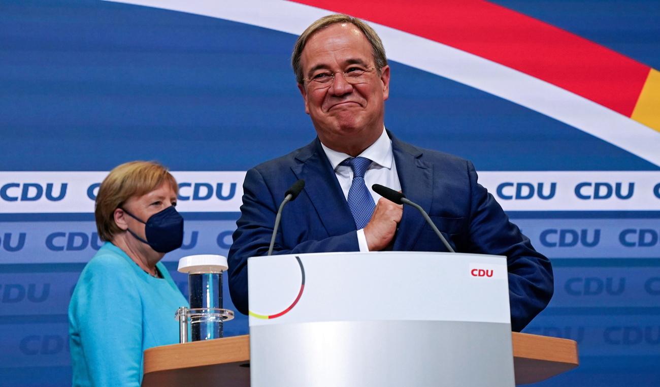 Armin Laschet, devant Angela Merkel, devant l'assemblée des militants de la CDU, après la proclamation des premiers sondages post-électoraux. [EPA/Keystone - CLEMENS BILAN]