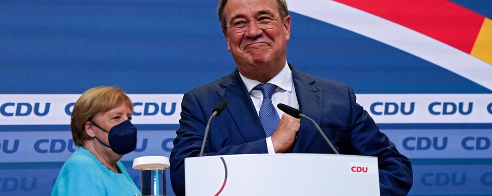 Armin Laschet, devant Angela Merkel, devant l'assemblée des militants de la CDU, après la proclamation des premiers sondages post-électoraux. [EPA/Keystone - CLEMENS BILAN]