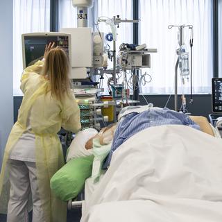 Une infirmière au chevet d'un patient atteint du Covid-19 dans l'unité de soins intensifs de l'hôpital de l'Ile à Berne le 16 décembre 2020. [Keystone - Peter Schneider]