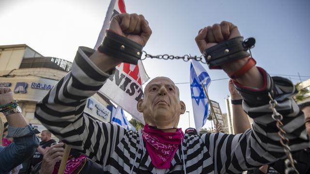 Un manifestant avec un masque à l'effigie du Premier ministre israélien Benjamin Netanyahu devant le tribunal de district de Jérusalem. [Keystone/EPA - Atef Safadi]